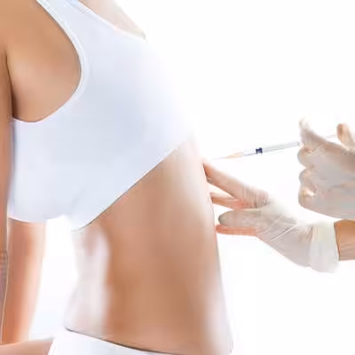 Person in a white top receives an injection in their abdomen from a gloved medical professional.